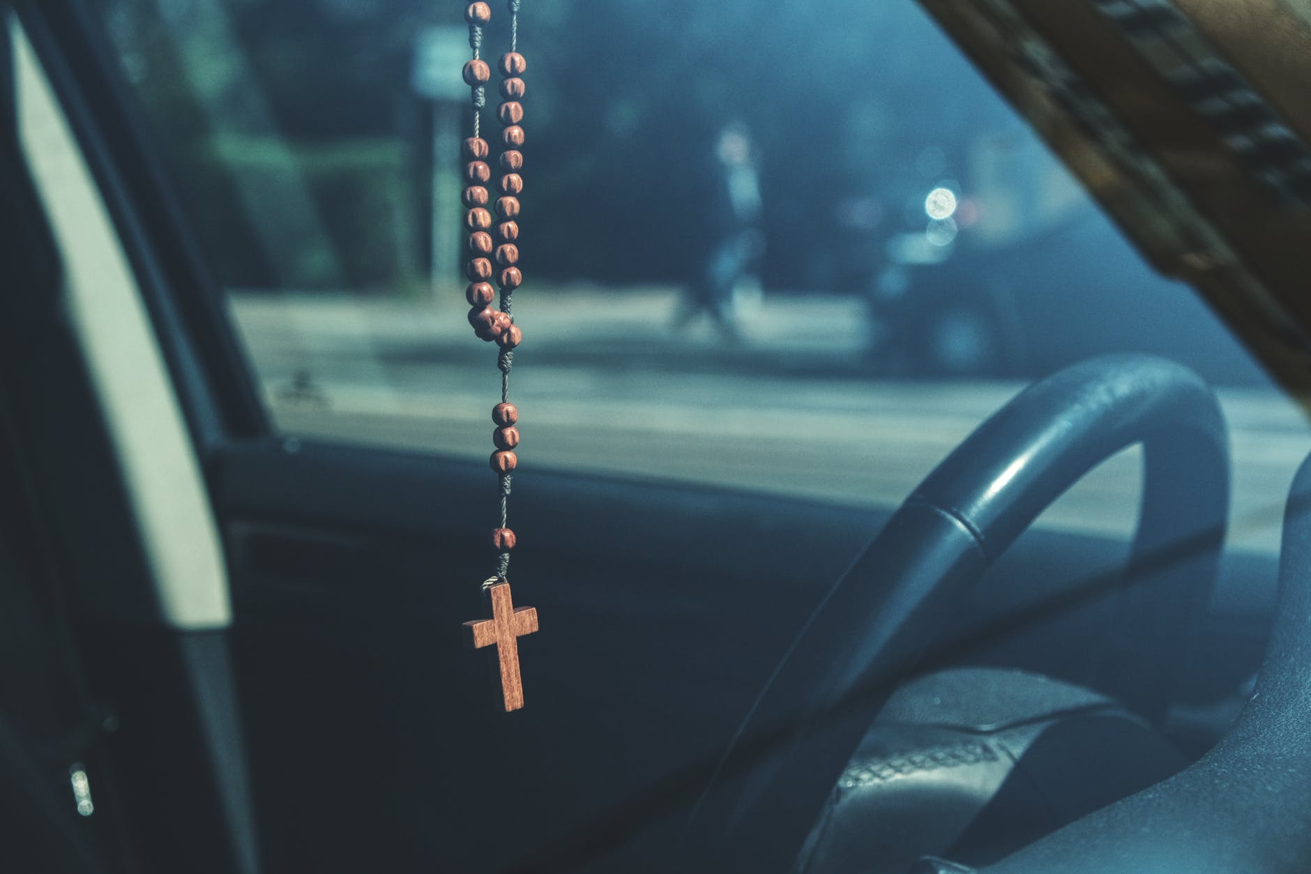 brown rosary dangling on car s rear view mirror